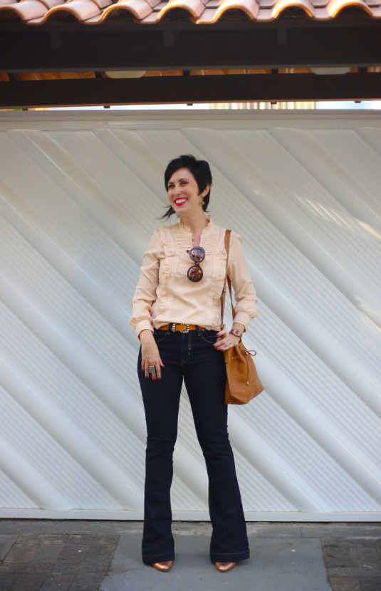 camisa rosê com drapeados e frufrus, calça flare jeans escura, scarpin dourado, bolsa saco caramelo